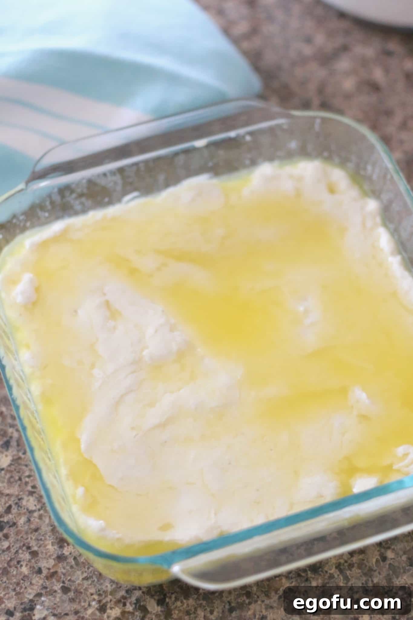 Golden Butter Biscuits 10 Buttermilk Swim Biscuit Batter pressed into the melted salted butter in a Pyrex square baking dish.