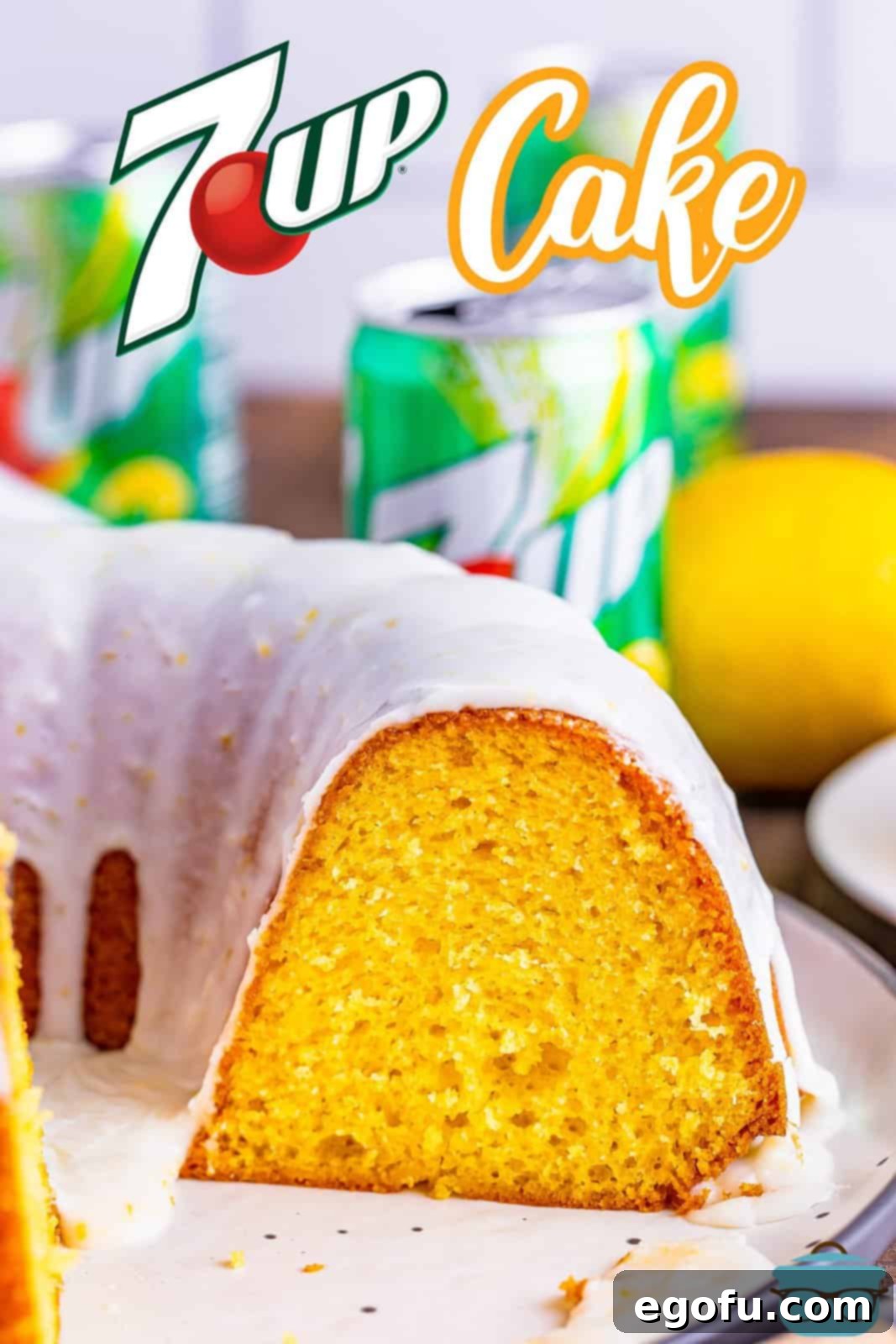 A freshly baked 7Up bundt cake, with a slice already removed, showcased on a pristine white plate. In the blurred background, several cans of 7Up soda are visible, emphasizing the cake's signature ingredient and refreshing flavor profile.