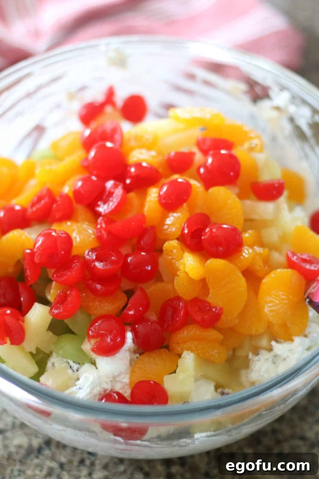 Southern Ambrosia Delight 7 Mandarin orange slices, sliced maraschino cherries, pineapple tidbits and sliced green grapes added to a large clear bowl with cool whip.