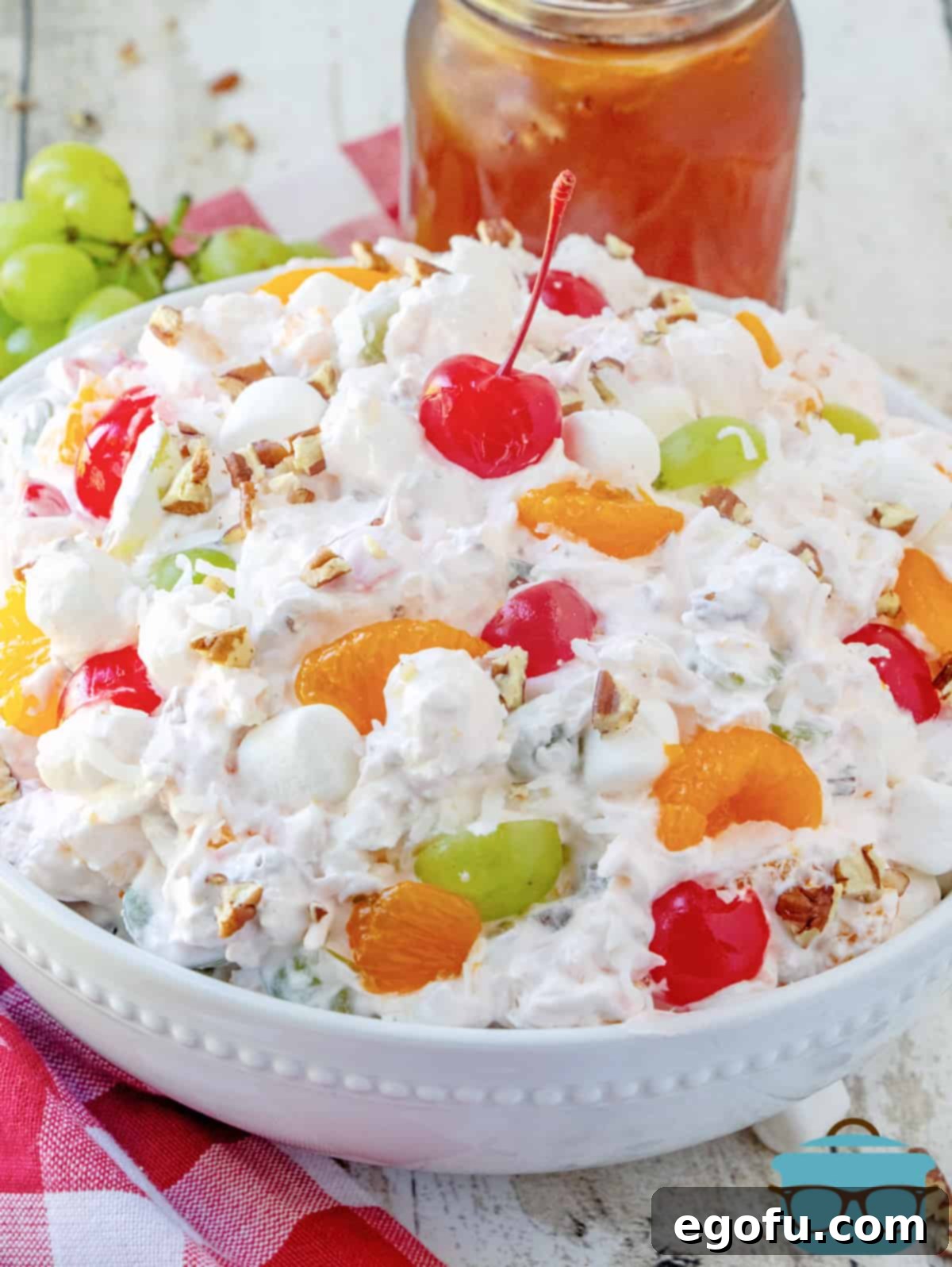 Southern Ambrosia Delight 8 A large white bowl with ambrosia salad in it with a glass of iced tea in the background.