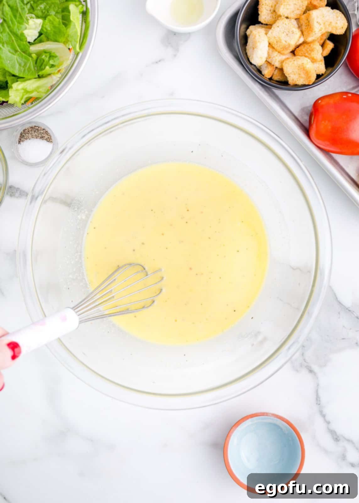 A close-up of the dressing being whisked in a bowl until smooth.