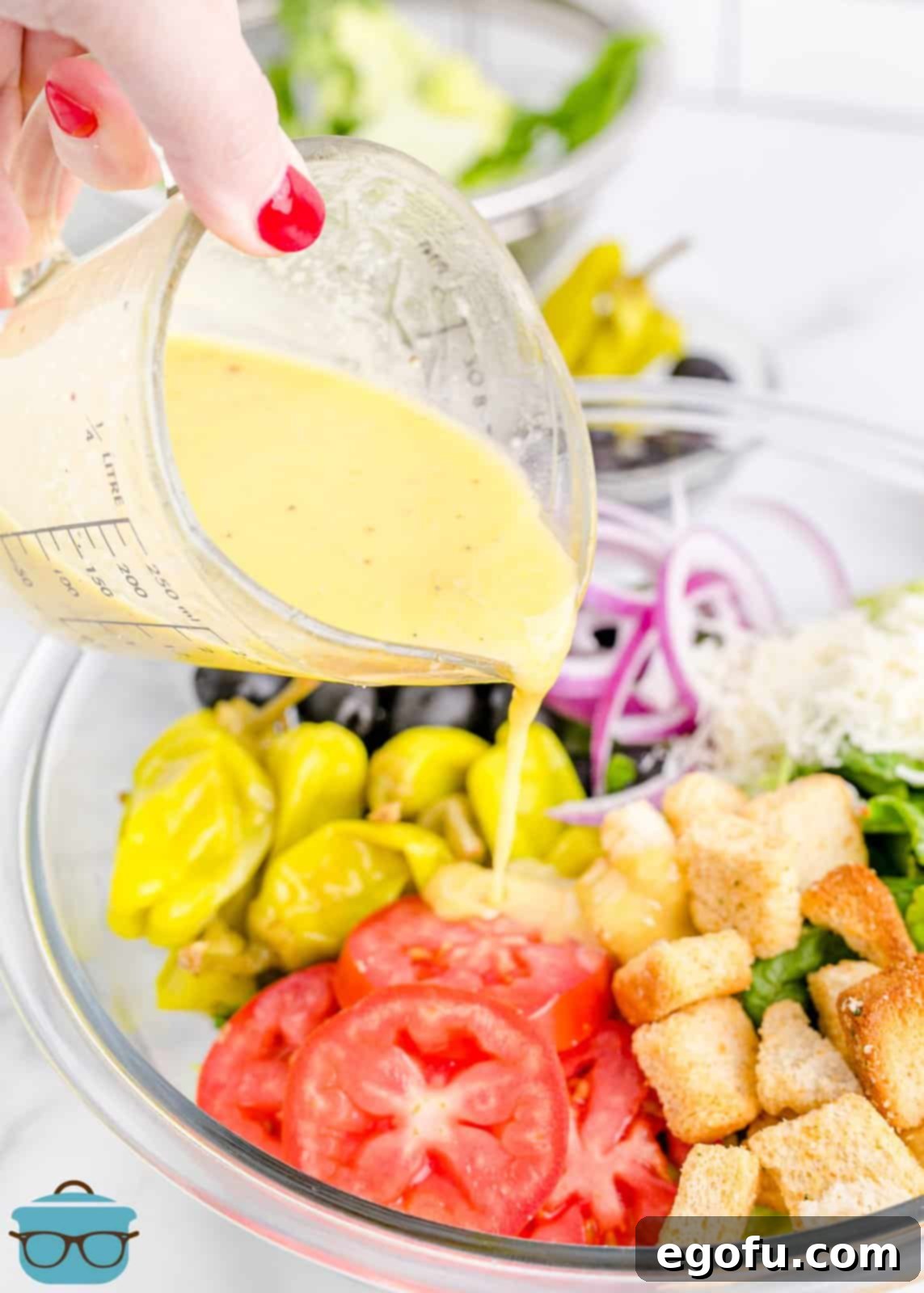 Homemade Olive Garden Salad Dressing being poured over a fresh salad in a large bowl.