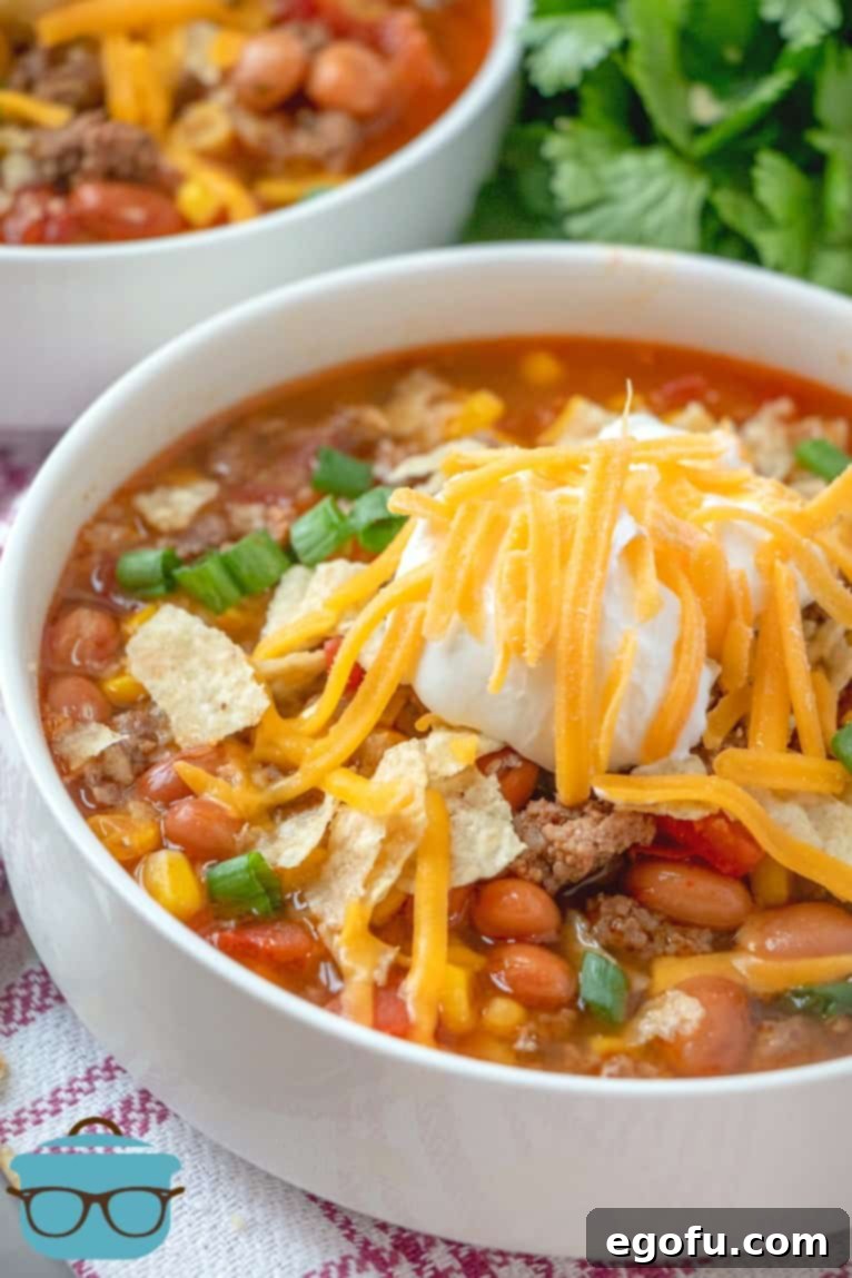Hearty Slow Cooker Taco Soup 8 a bowl of taco soup topped with tortilla chips, sour cream and shredded cheese.