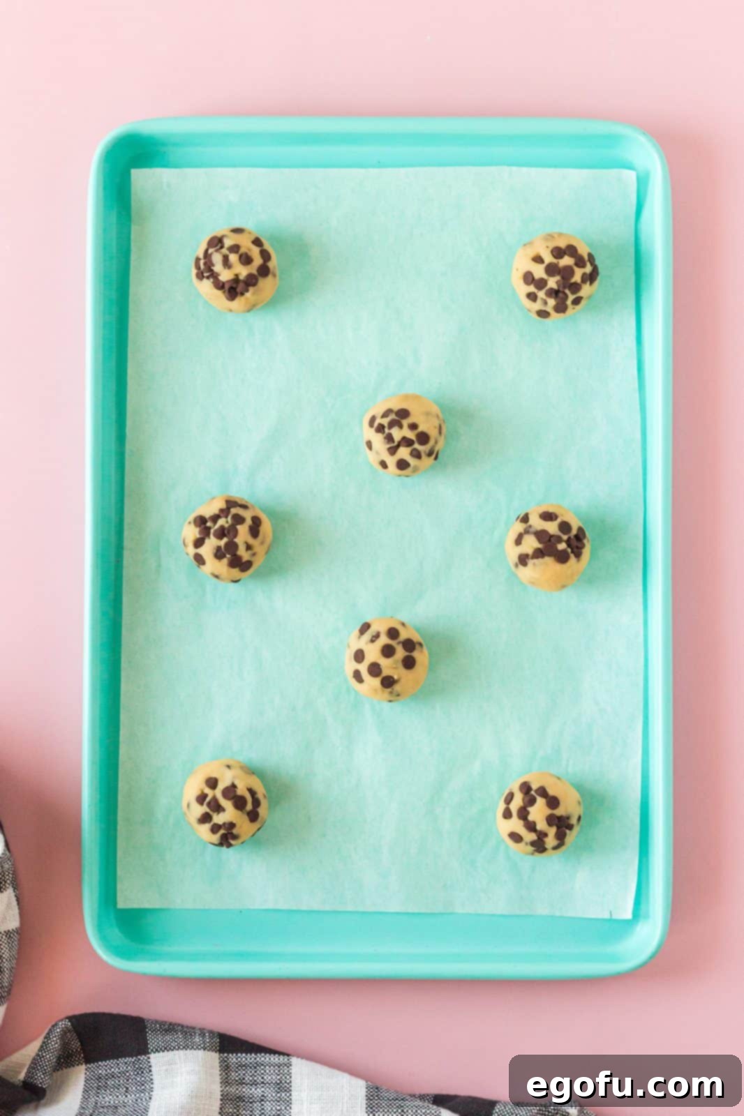Neatly scooped, round cookie dough balls arranged on a parchment-lined baking sheet, ready for chilling and baking.