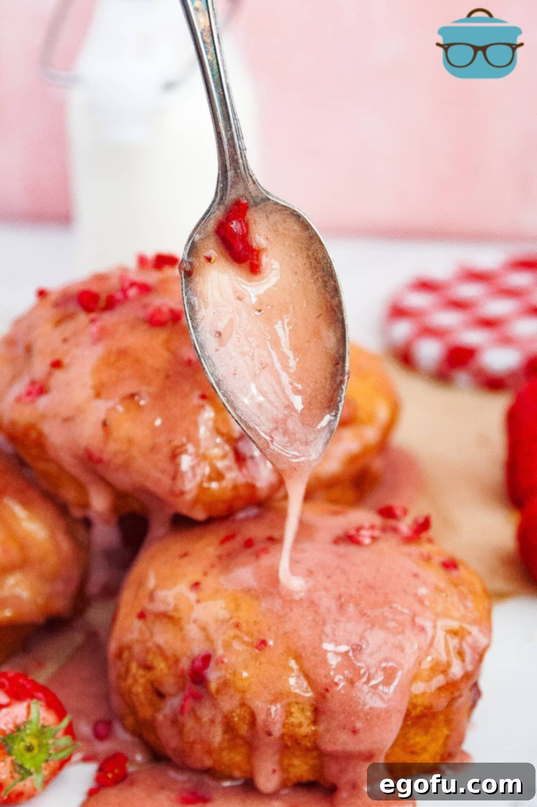 Spoon drizzling glaze over top of one Strawberry Jelly Filled Biscuit Donut.