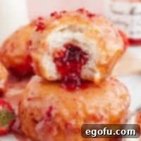 Square image of finished Strawberry Jelly Filled Biscuit Donuts with bite taken out of one.