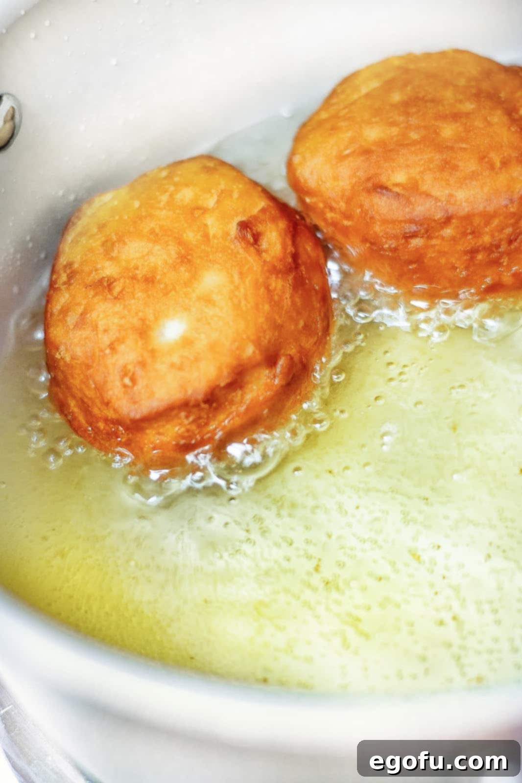 Biscuits flipped over in oil showing browned side.