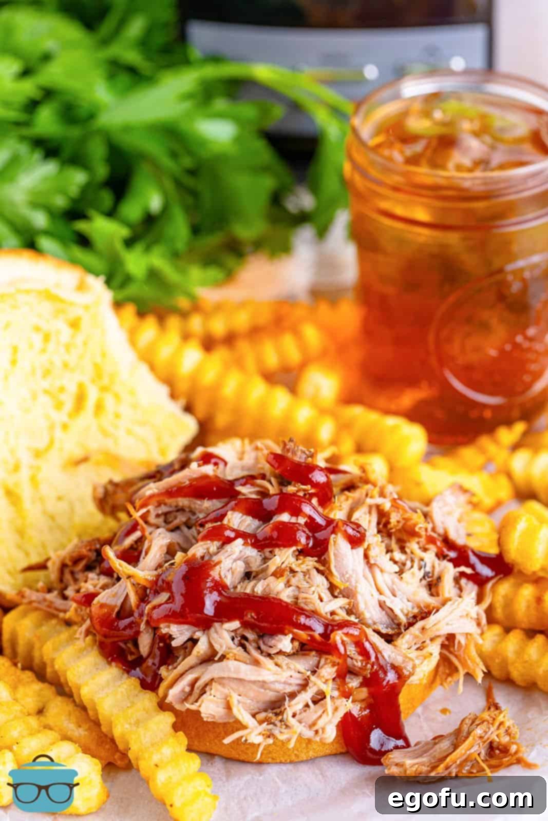 Pulled pork served on an open-faced bun with BBQ sauce drizzled generously on top.