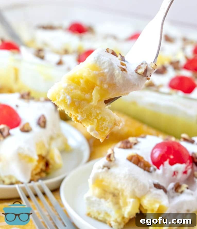 A forkful of No-Bake Twinkie Cake ready to be enjoyed, with the full baking dish visible in the background.