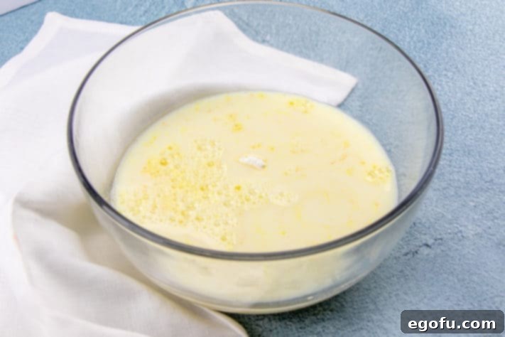 Instant vanilla pudding mix being poured into a bowl with cold milk.