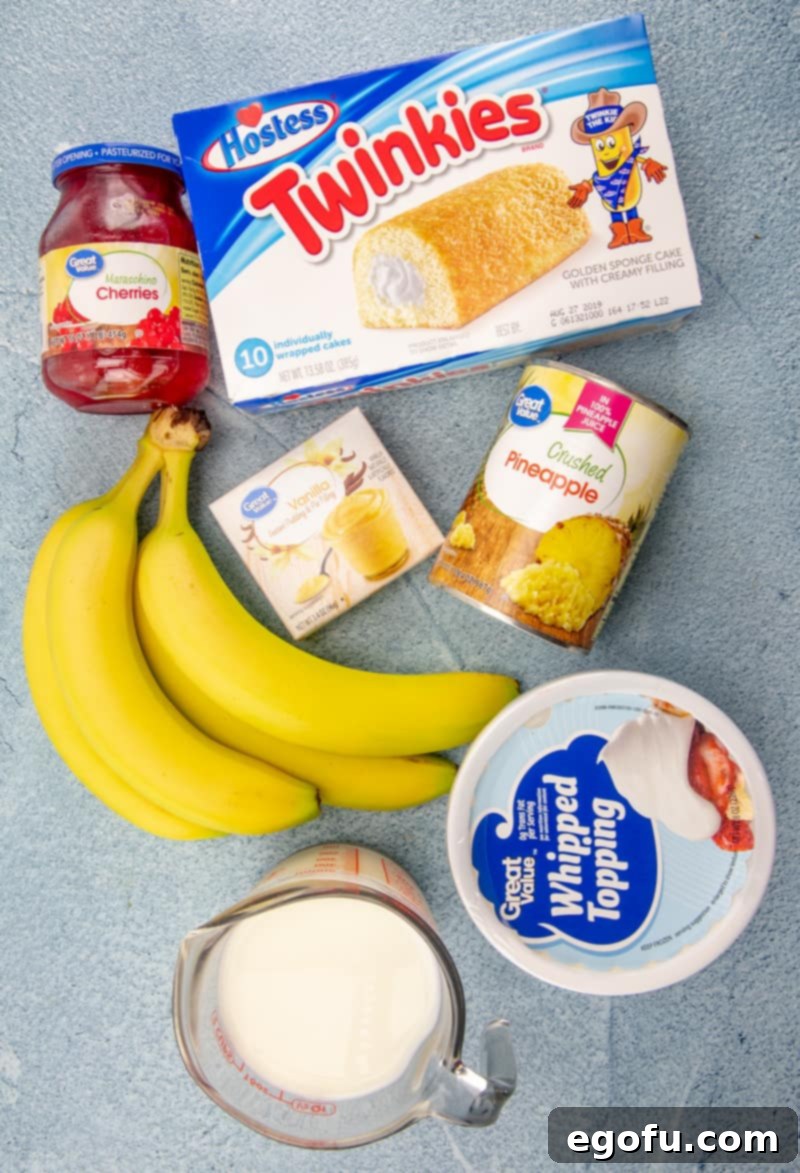 A vibrant flat lay photo displaying all the ingredients needed for No-Bake Twinkie Cake: Twinkies, fresh bananas, crushed pineapple, instant vanilla pudding mix, milk, whipped topping, maraschino cherries, and chopped nuts.