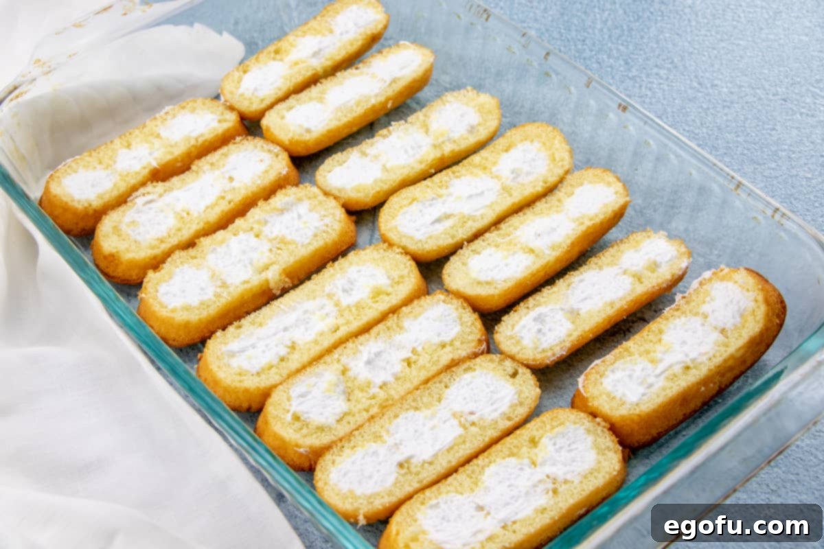 Cream side up, neatly sliced Twinkies forming the base layer in a 9x13 inch baking pan.