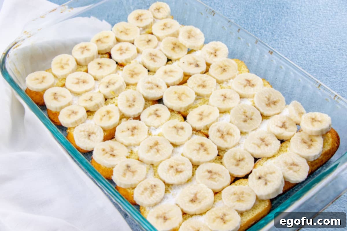 Freshly sliced bananas arranged over the Twinkie layer in the baking pan.