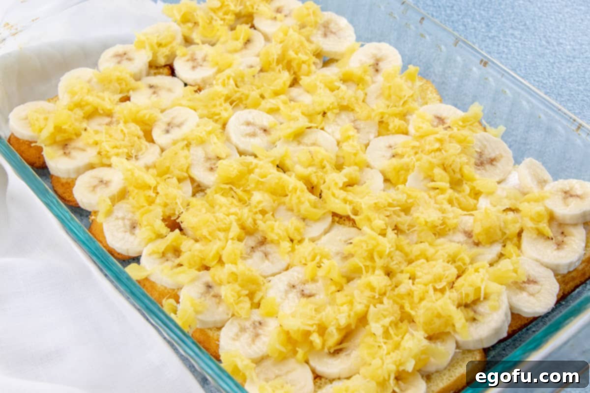 Crushed pineapple spread evenly over the banana layer in the baking pan.