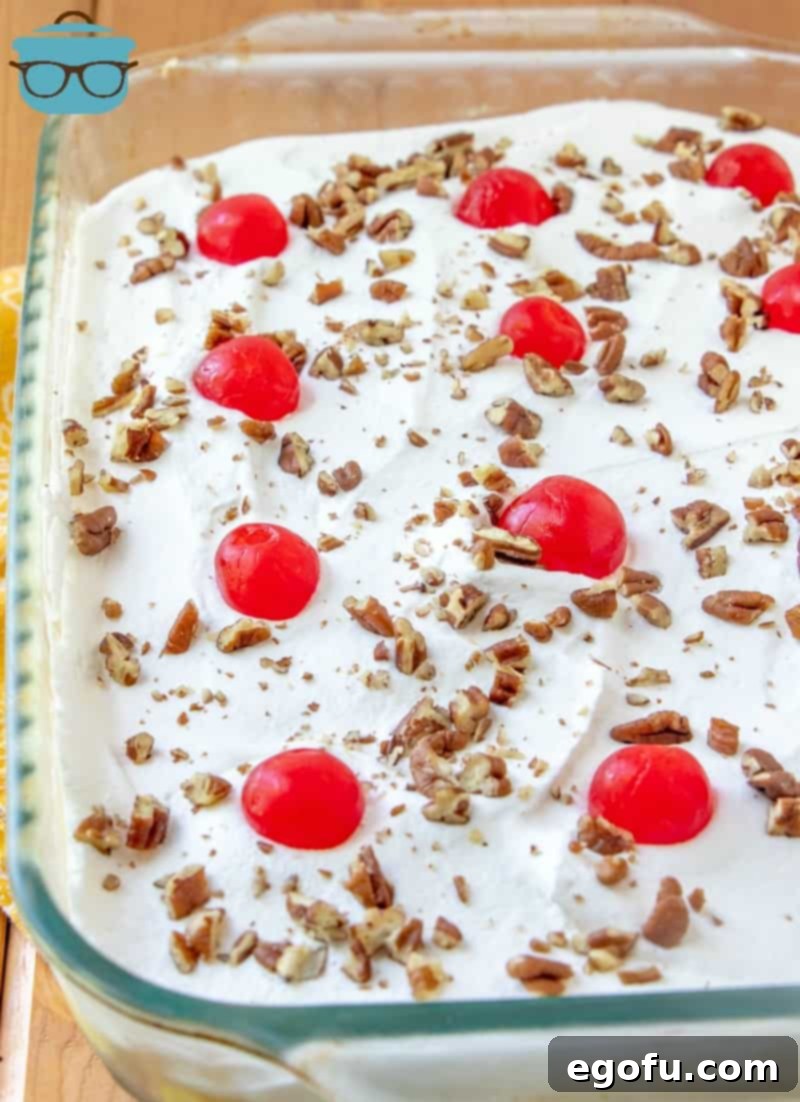 The fully layered Twinkie Cake topped with a sprinkle of chopped nuts and bright red maraschino cherries.