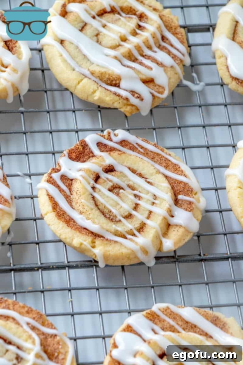 Cooled cinnamon roll cookies on a cooling rack drizzled lightly with white icing, looking irresistible.