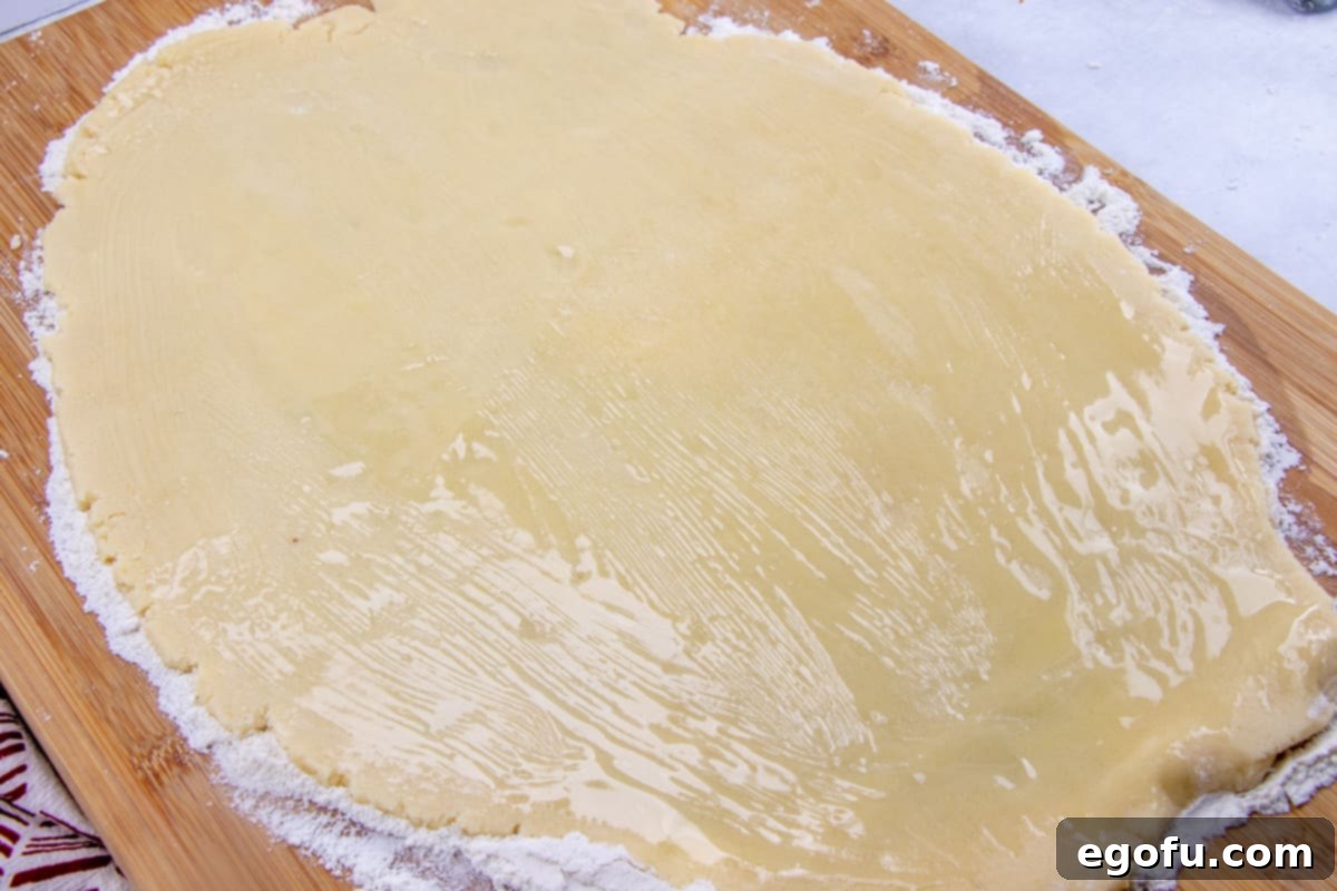Rolled out sugar cookie mix spread with melted butter, ready for the cinnamon sugar.
