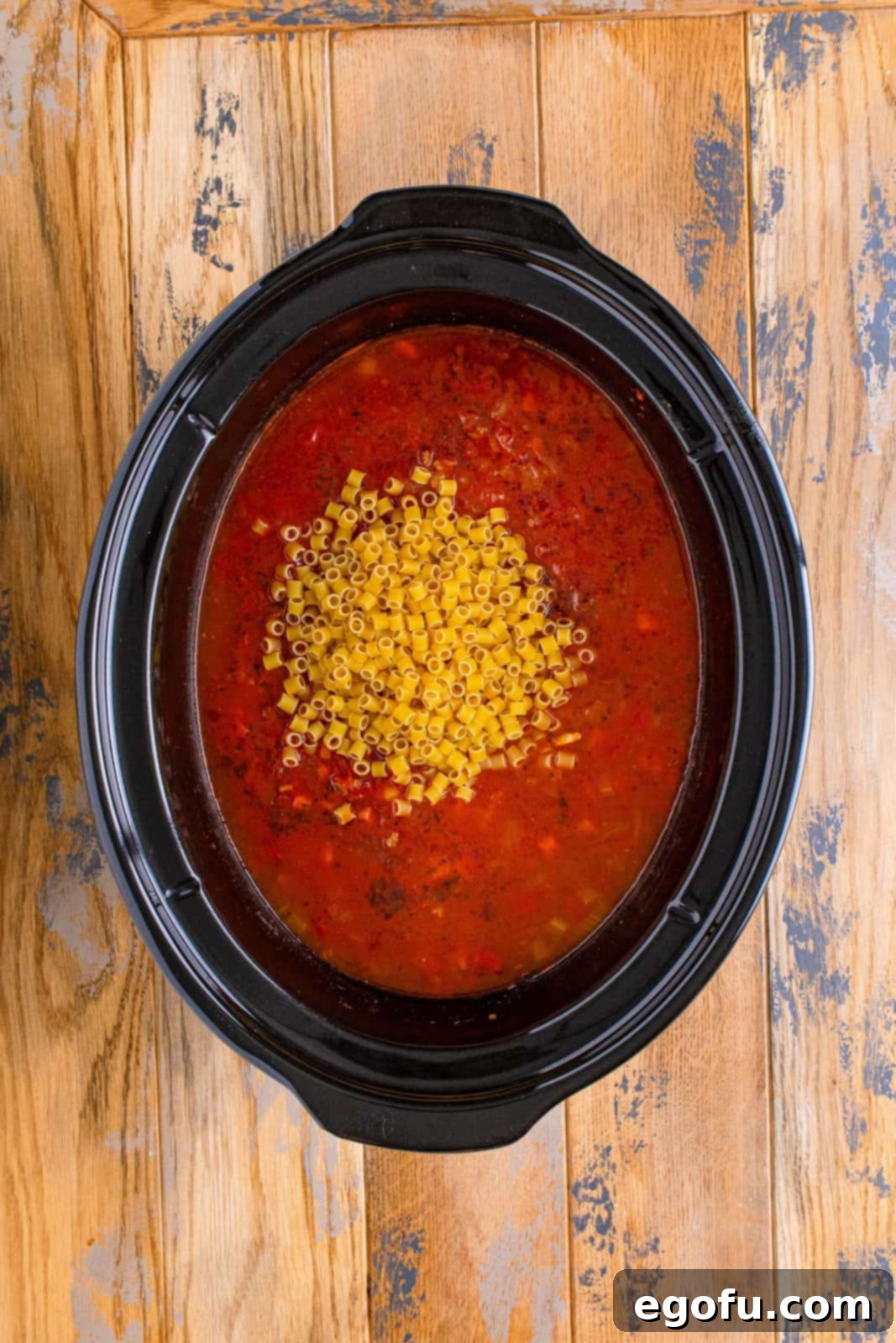 uncooked ditalini pasta added to slow cooker. 