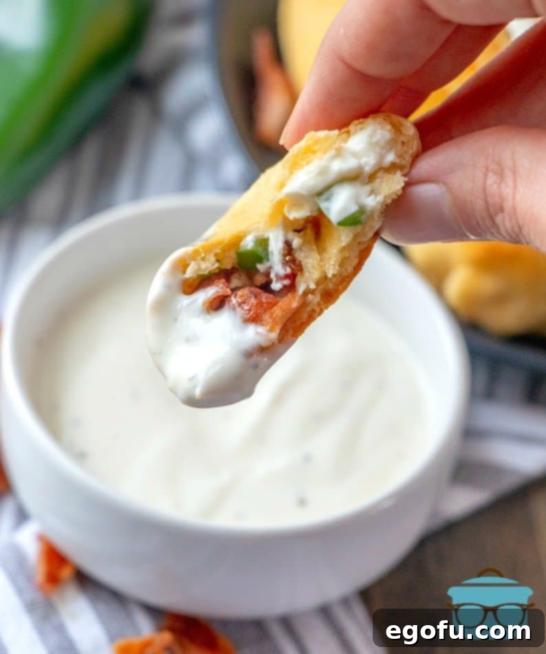Zesty Jalapeño Delights 11 A delicious Jalapeño Popper Bite being dipped into a swirl of creamy ranch dressing, highlighting the perfect pairing.