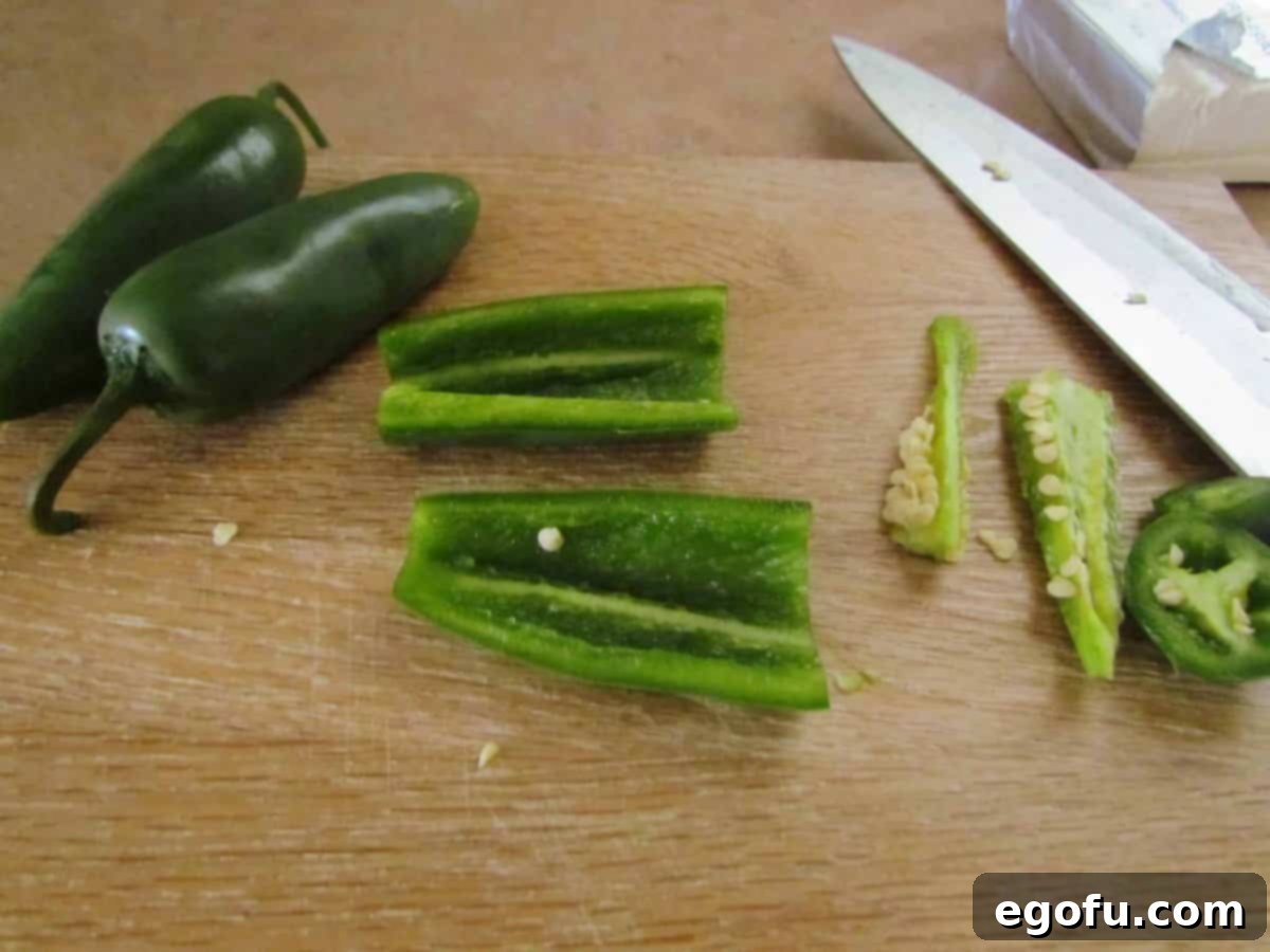 Zesty Jalapeño Delights 6 A cutting board with sliced and diced jalapeños, prepared and ready to be incorporated into the creamy filling.