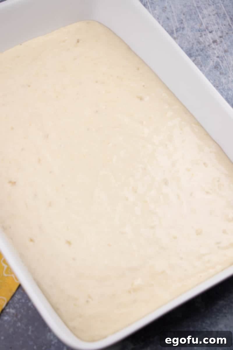 Smooth banana cake batter has been perfectly poured into a ready 9x13-inch baking dish, prepared for its journey into the oven.