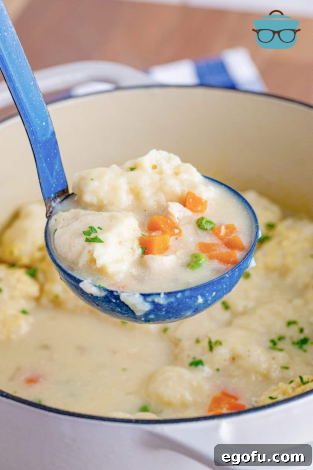 a blue ladle scooping up some Chicken and Bisquick dumplings from a large white pot. 