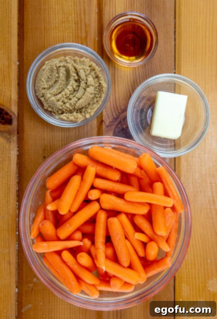 Maple Kissed Carrots 4 The four simple and fresh ingredients for maple glazed carrots laid out: a stick of golden salted butter, a bowl of rich brown sugar, a bottle of amber maple syrup, and a bag of vibrant baby carrots.