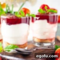 No-Bake Strawberry Cheesecake Parfaits 11 A square, close-up photo of a finished Strawberry Cheesecake Parfait presented on a rustic wooden board, clearly displaying its beautiful, distinct layers of graham cracker, creamy filling, and strawberry topping.