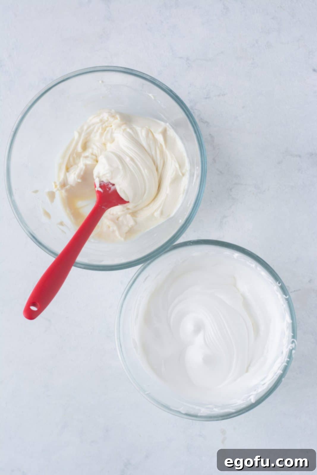 No-Bake Strawberry Cheesecake Parfaits 7 The smooth and creamy cheesecake ingredients being gently folded together in a mixing bowl with a spatula, ensuring the airy texture is maintained.