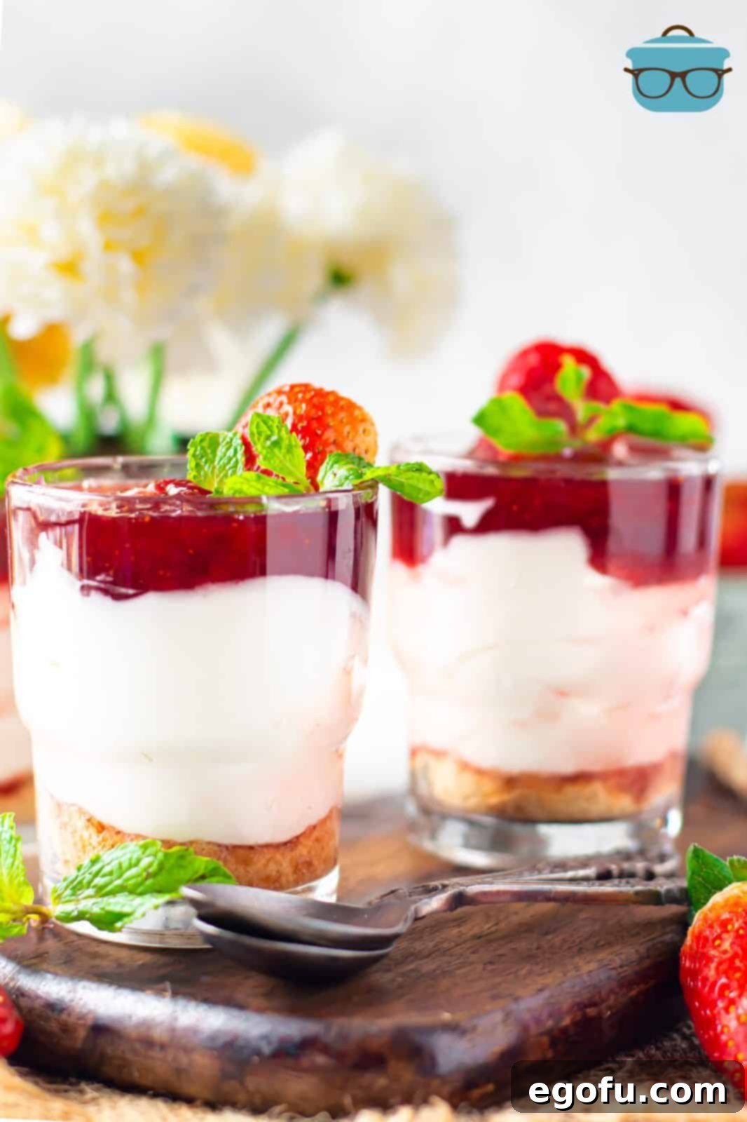 No-Bake Strawberry Cheesecake Parfaits 10 A straight-on, beautifully composed photo of a finished Strawberry Cheesecake Parfait, clearly showcasing its distinct, appealing layers of graham cracker, creamy cheesecake, and vibrant strawberry topping, garnished with fresh fruit.