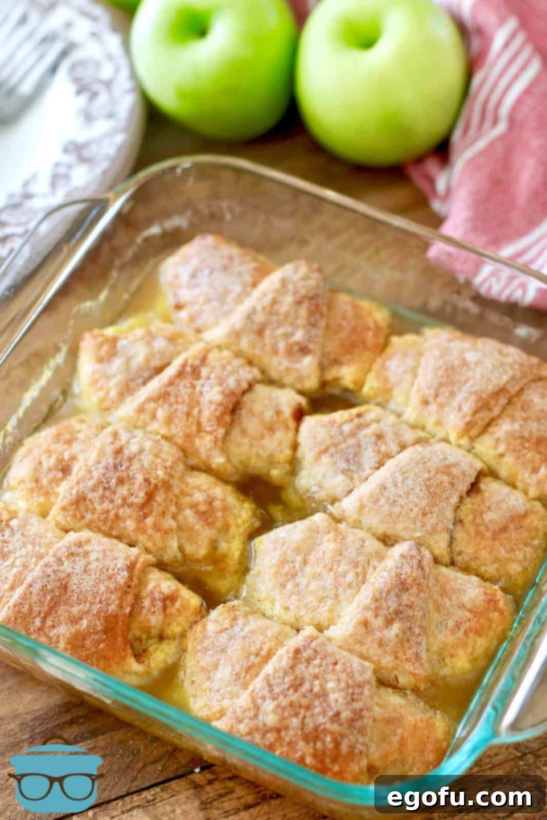Sweet Apple Pockets 13 A close-up shot of fully baked, golden-brown apple dumplings, glistening with their sweet, bubbly sauce, sitting warm in a glass baking dish.