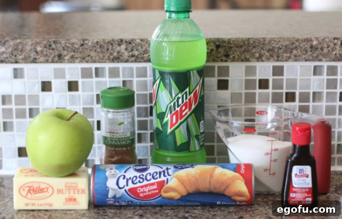 Sweet Apple Pockets 4 A flat lay photograph showcasing all the ingredients required for Easy Apple Dumplings: a vibrant green apple, a tube of crescent rolls, a stick of butter, granulated sugar, a bottle of vanilla extract, ground cinnamon, all-purpose flour, and a bottle of lemon-lime soda.