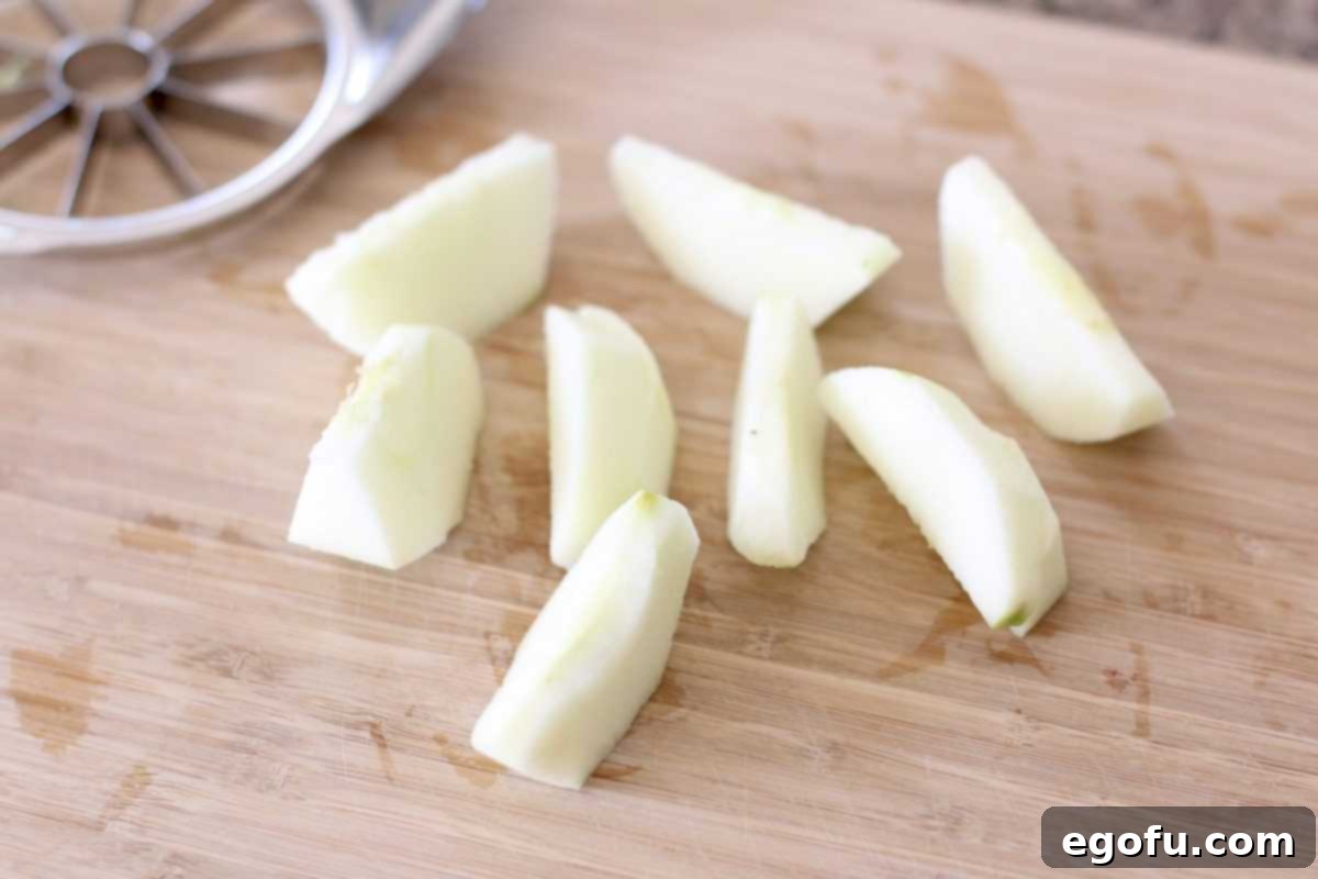 Sweet Apple Pockets 6 Eight neatly cut apple slices, peeled and cored, arranged on a wooden cutting board, ready for the next step of the dumpling recipe.