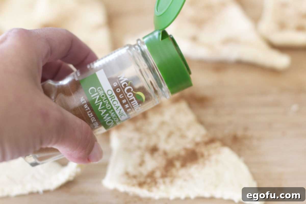 Sweet Apple Pockets 7 A crescent roll dough triangle laid flat on a surface, with a light dusting of ground cinnamon sprinkled over its wider end, ready for an apple slice.