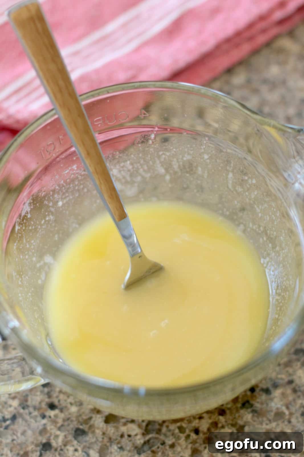 Sweet Apple Pockets 10 A smooth, golden mixture of melted butter, sugar, flour, and vanilla extract in a clear glass bowl, just mixed and ready to be poured.