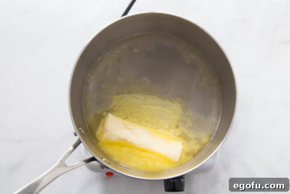 Melted butter in a small saucepan with water, ready for flour.