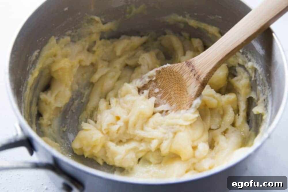 Homemade cream puff dough forming a paste after flour is added to butter and water.
