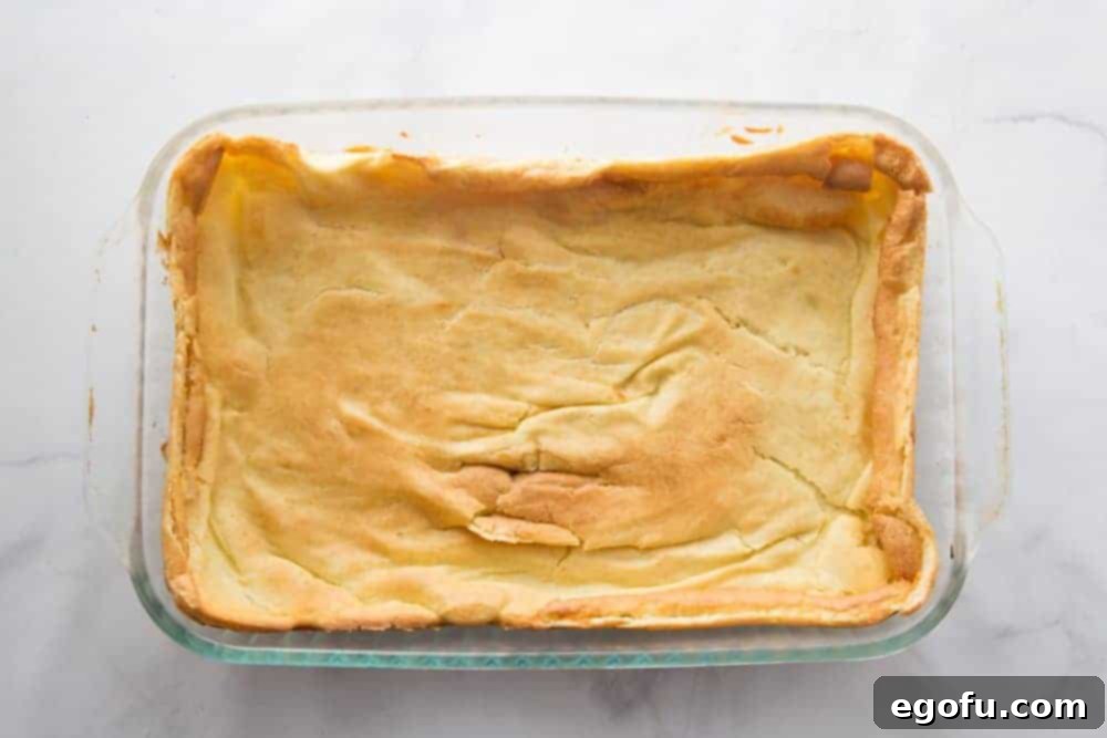Cream puff pastry layer fully baked to golden brown in a clear baking dish.