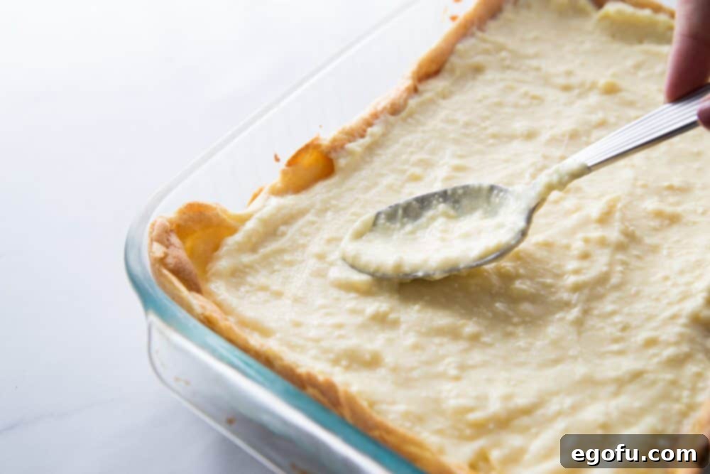 Cream cheese vanilla pudding spread smoothly on top of the cream puff pastry layer.