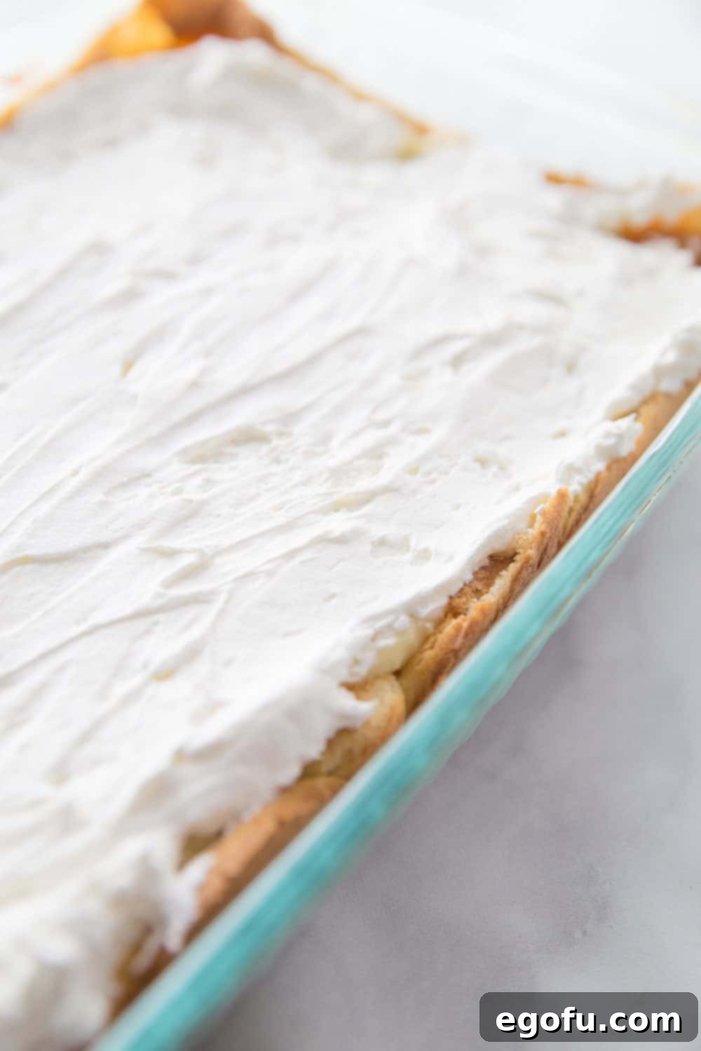 Cool Whip spread on top of the vanilla pudding layer in a 9x13 baking dish.