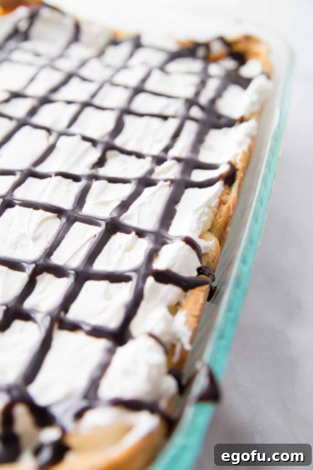 Chocolate syrup elegantly drizzled on top of the finished cream puff dessert.