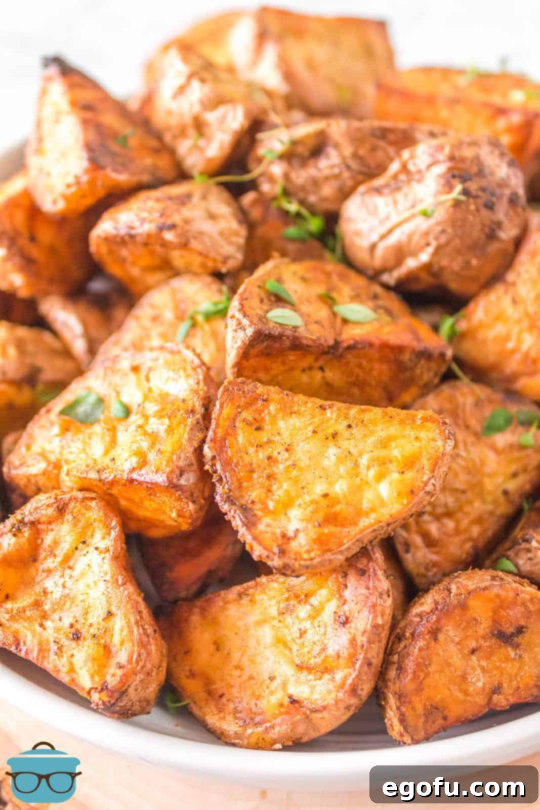 Close up of perfectly golden and crispy Air Fryer Roasted Red Potatoes in a rustic bowl, garnished lightly with fresh herbs.