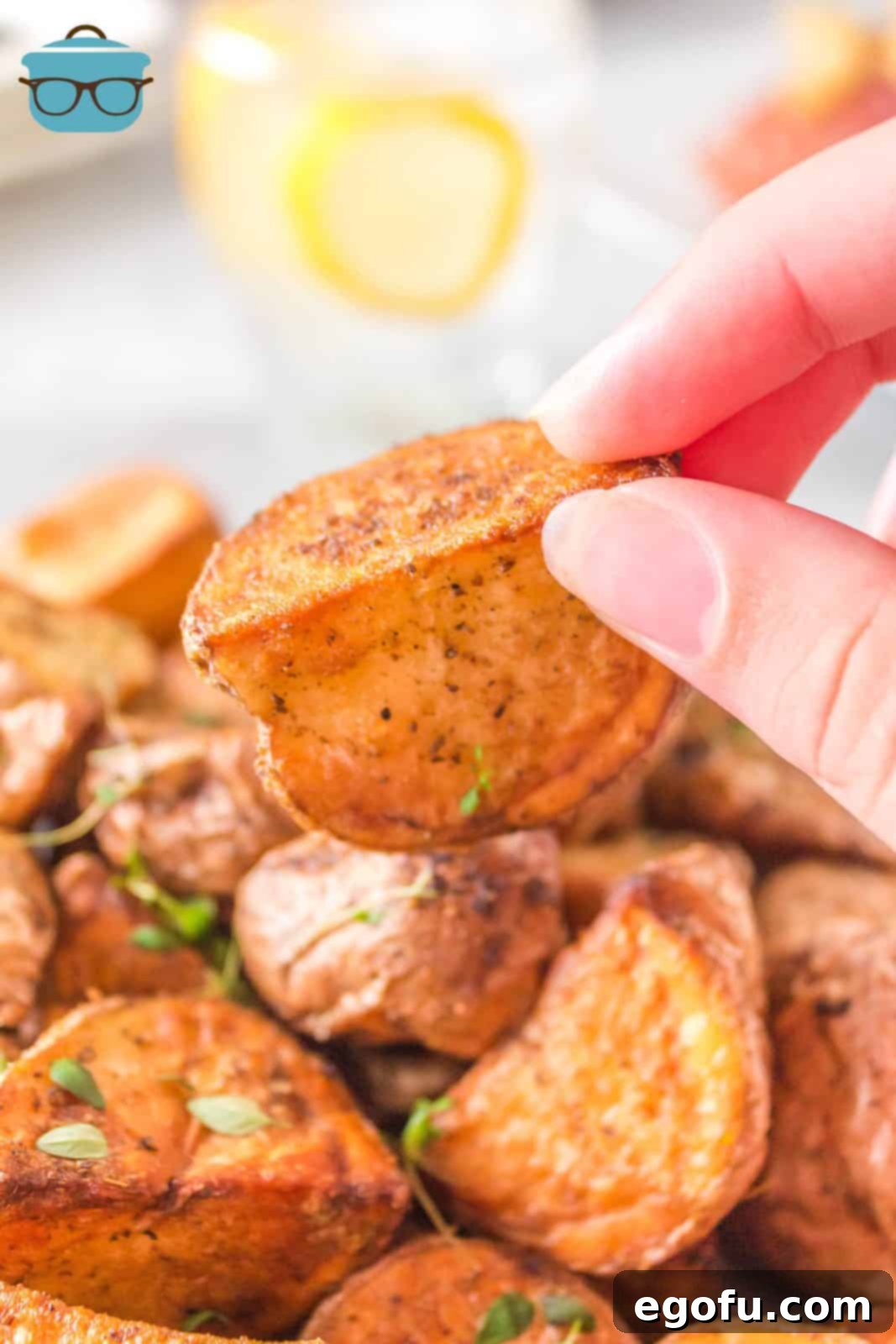 A hand holding up one perfectly roasted, crispy Air Fryer Red Potato, showcasing its golden exterior.