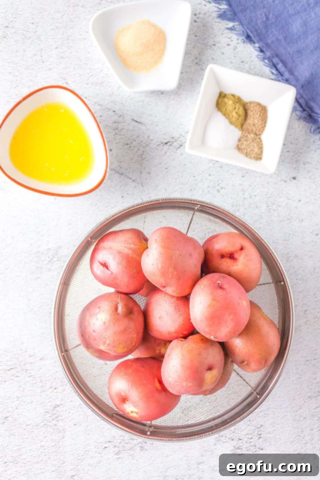 All ingredients laid out: red baby potatoes, salted butter, garlic powder, salt, pepper, celery seeds, and ground thyme, ready for preparation.