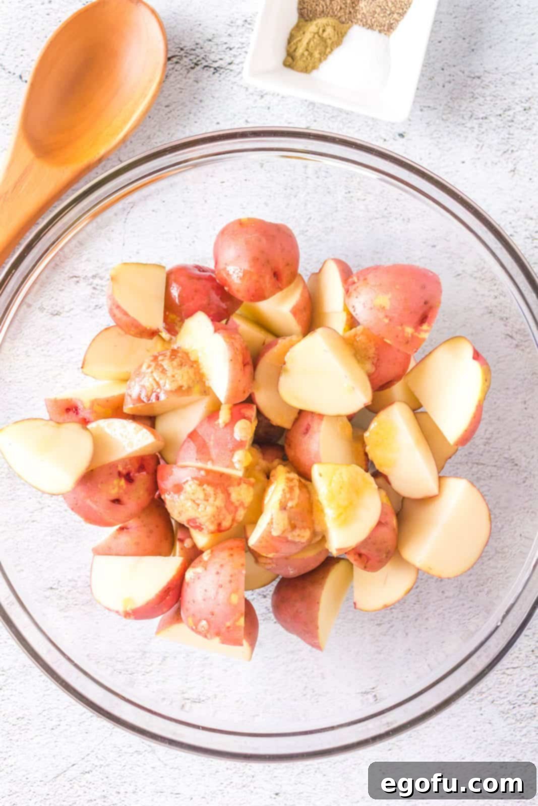Quartered potatoes thoroughly tossed in the butter and garlic powder mixture, glistening and ready for more seasoning.
