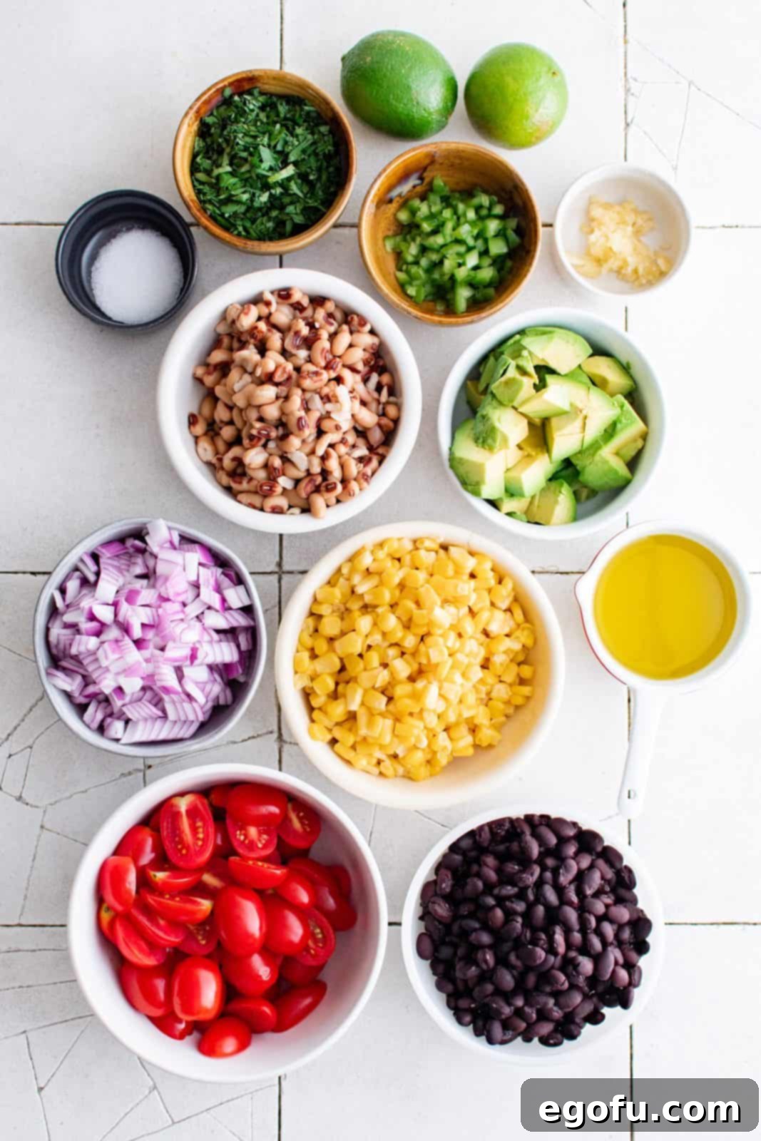 Western Whimsey Dip 4 A colorful array of fresh ingredients laid out: sweet golden corn, black beans, black eyed peas, baby tomatoes, cilantro, red onion, jalapeño, garlic, olive oil, lime juice, salt and avocado.