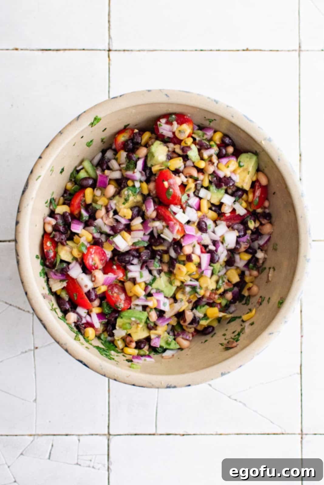 Western Whimsey Dip 5 Avocado added to a bowl of Cowboy Caviar and gently tossed together to combine the ingredients.