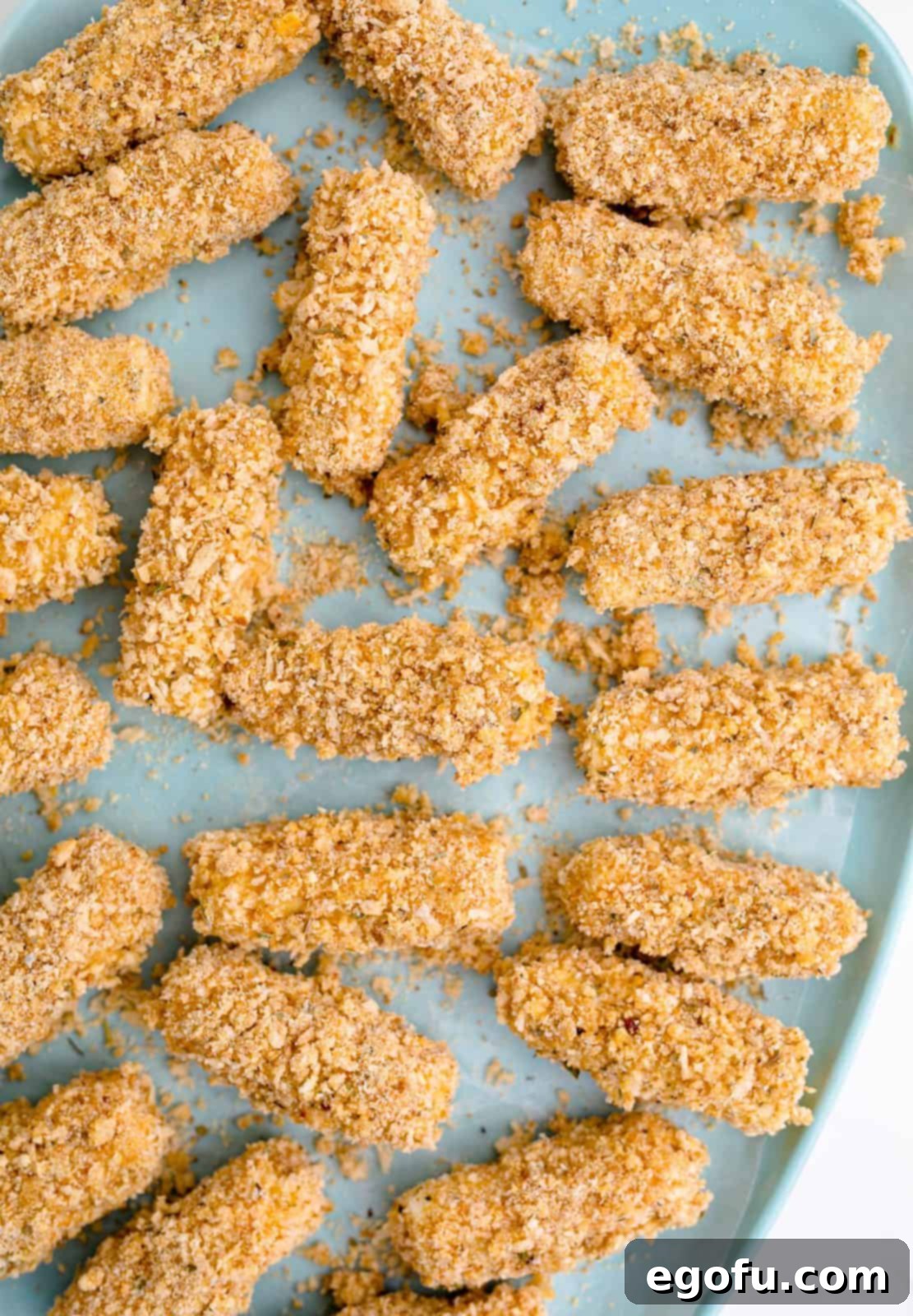 Coated cheese sticks on pan.