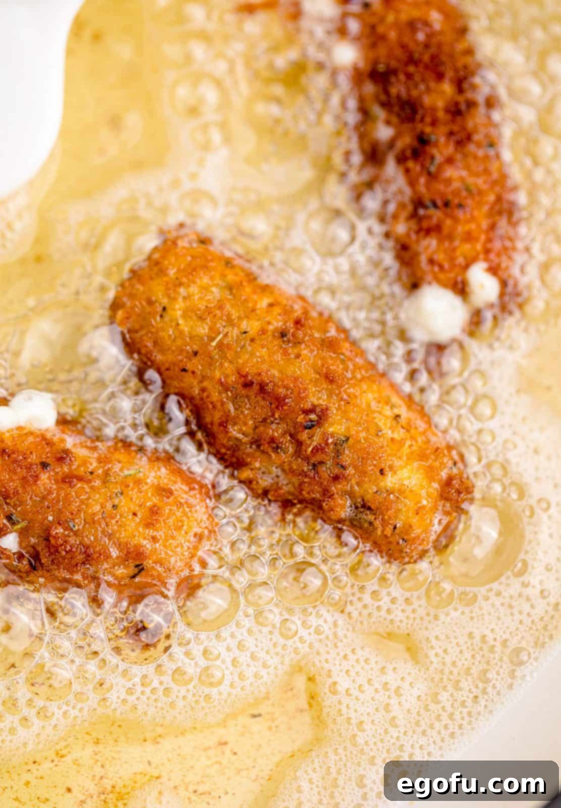 Mozzarella sticks frying in oil.