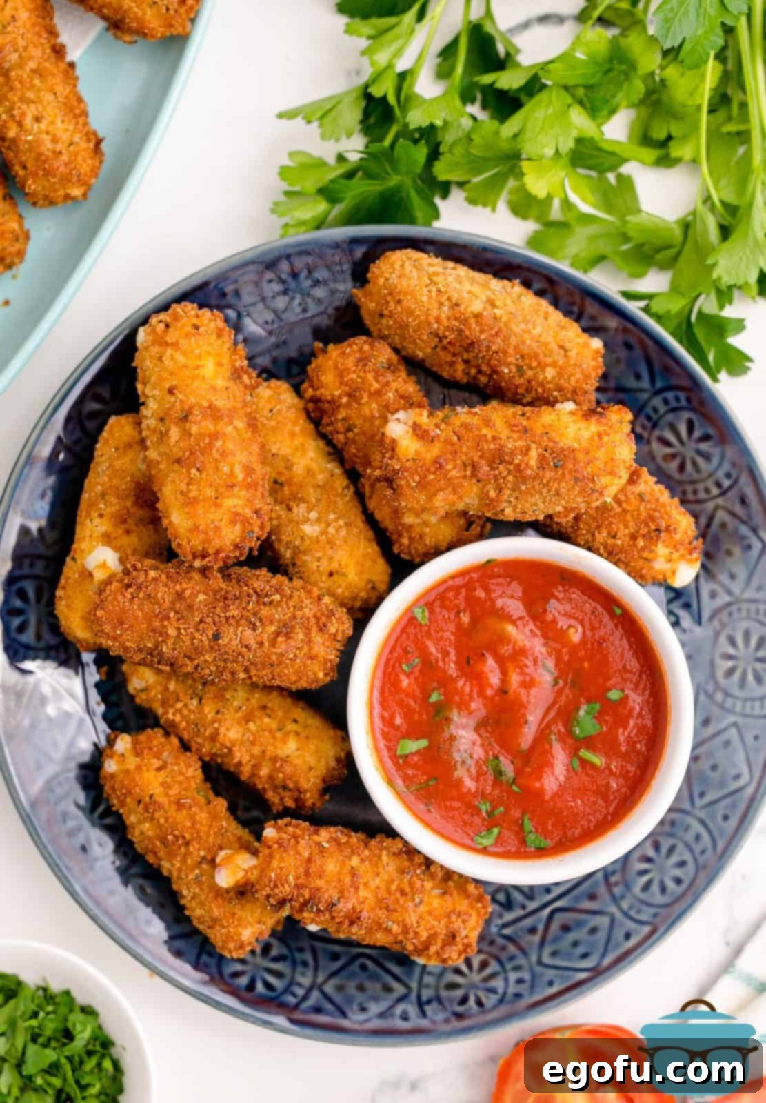 Overhead photo of Homemade Mozzarella Sticks on plate with sauce.